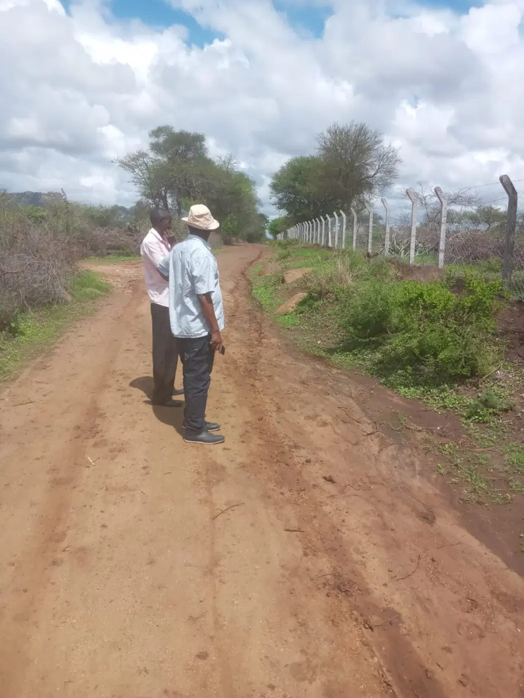 Alumni walk the perimeter to inspect the fencing work.