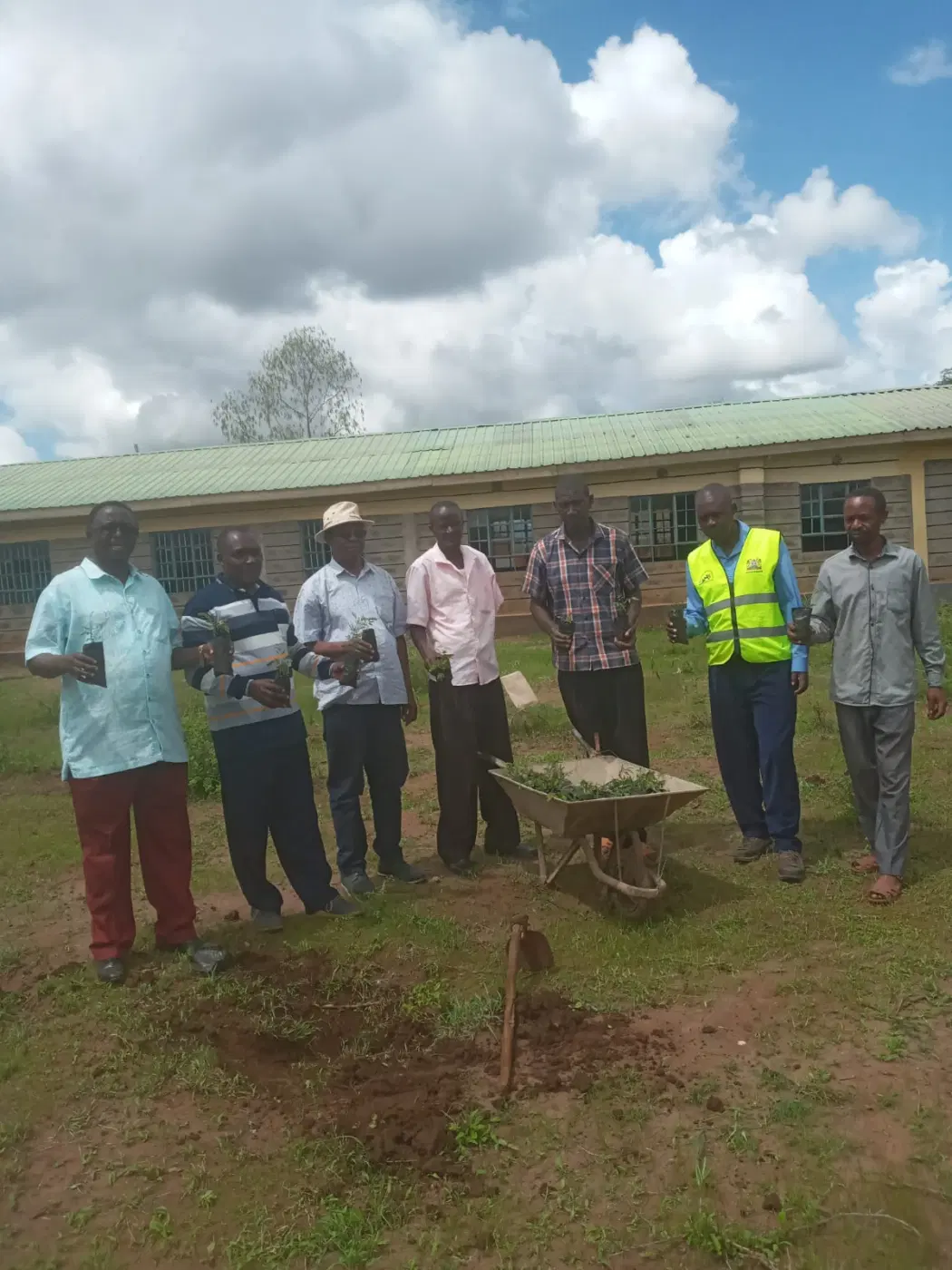 A group marks the planting day beside a young tree.