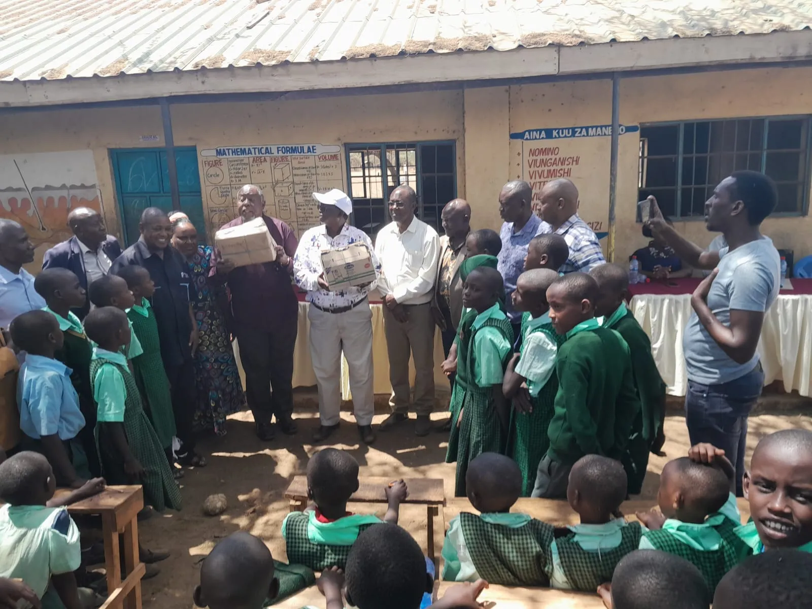 Alumni present learning materials to pupils during a school visit.